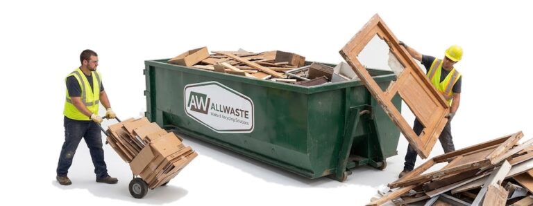 Two workers loading demolition debris into a roll-off container