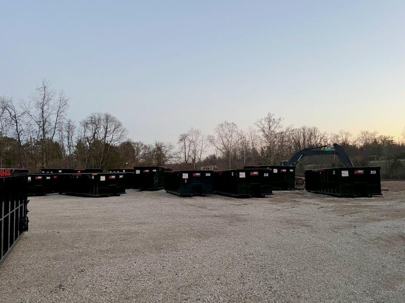 Roll-off containers lined up in the yard at dusk