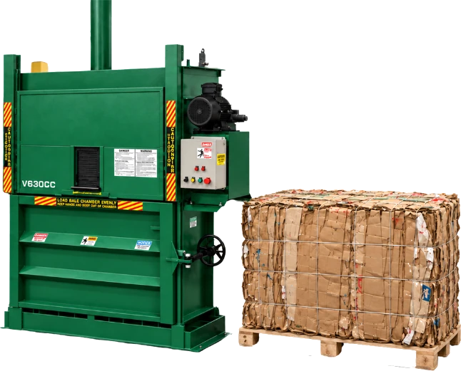 A green V630CC vertical cardboard baler beside a finished bale of cardboard on a pallet