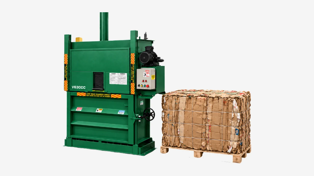 A green V630CC vertical cardboard baler beside a finished bale of cardboard on a pallet