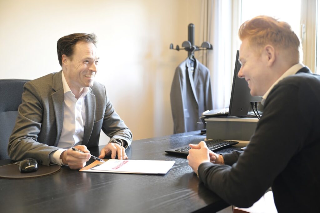Two people talking across a desk in an office