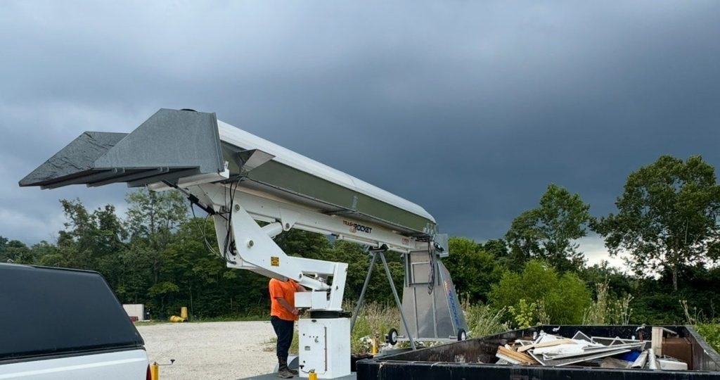 Trash Rocket chute extended over a roll-off container full of debris