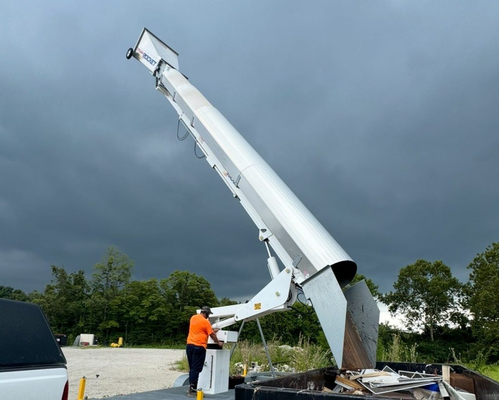 Trash Rocket chute raised on its trailer, with an operator at the control box